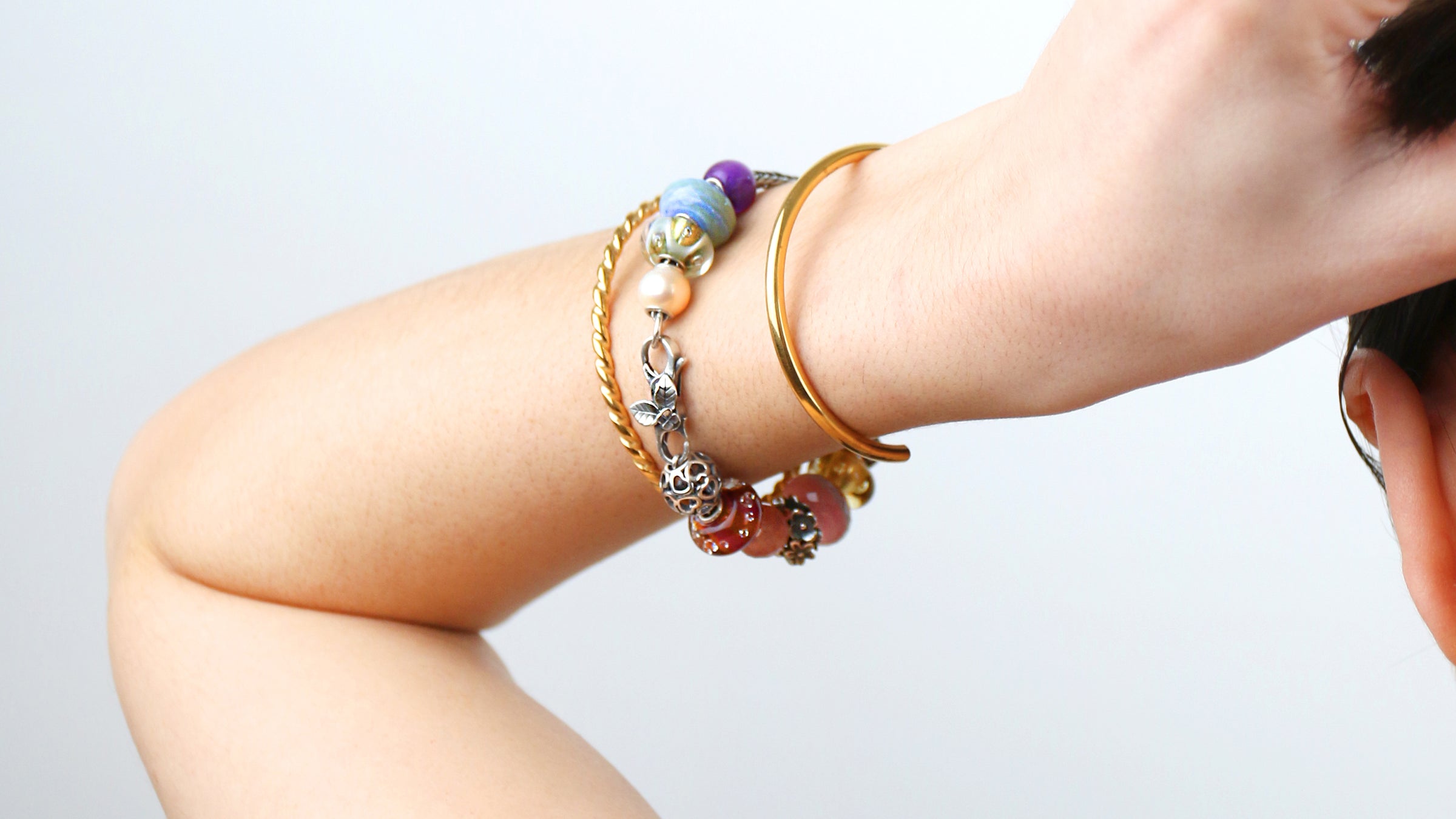 Gold bangles regular and twisted next to full silver foxtail bracelet with beads and flower clasp